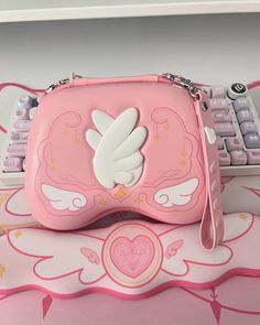 a pink purse sitting on top of a table next to a keyboard and mouse pad