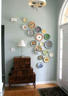 a room with plates on the wall and a dresser in front of it that is next to a doorway