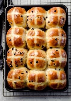 freshly baked hot cross buns in a baking pan on a cooling rack, ready to be eaten