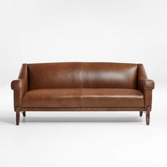 a brown leather couch sitting on top of a white floor next to a wooden frame