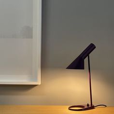 a desk lamp sitting on top of a wooden table next to a white framed wall