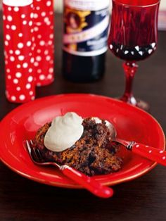 a red plate topped with a piece of cake next to a wine glass and bottle