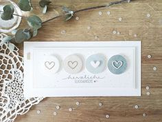 three heart shaped buttons on a card next to some flowers and lace doilys