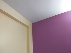 an empty room with a purple wall and white trim on the walls is seen in this image