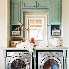 a washer and dryer in a laundry room with blue cabinetry above it