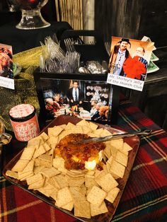 a plate full of nachos and chips with pictures on the table behind it