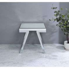 a white table sitting on top of a marble counter next to a potted plant