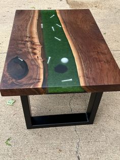 a table made out of wood and glass with a hole in the grass on it