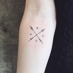 a woman's arm with an arrow and compass tattoo on the left inner arm