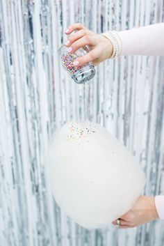 a person pouring confetti on top of a white ball with sprinkles