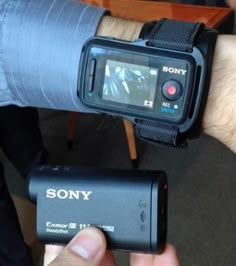 a man holding onto a smart watch with an external camera attached to it