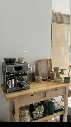 a coffee maker sitting on top of a wooden table in front of a white wall