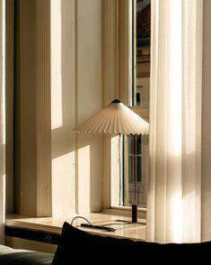 a lamp sitting on top of a window sill next to a curtained window