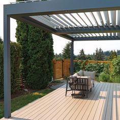 a wooden deck with chairs and table under a pergolated roof over looking a garden