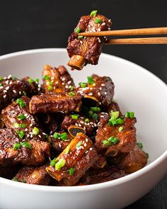 a white bowl filled with meat and chopsticks sticking out of the meat in it