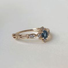 a gold ring with blue and white stones on it's side, sitting on a table