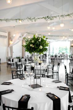 the tables are set up with black and white linens, silverware, and greenery