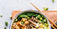 a bowl filled with noodles and vegetables next to chopsticks