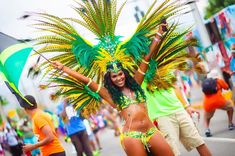 a woman in a green and yellow costume is dancing on the street with other people