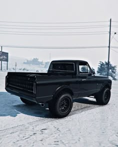 an old black truck is parked in the snow