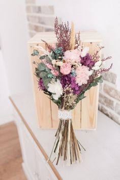 a bouquet of flowers sitting on top of a wooden shelf next to a brick wall