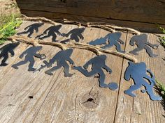 several metal cutouts of people running across a wooden plank with rope on the ground