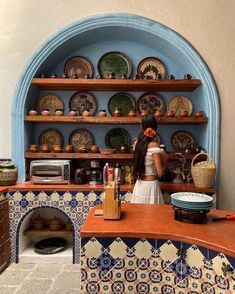 a woman standing in front of a counter filled with plates and bowls next to an oven