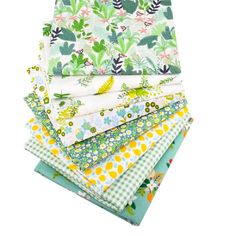 a stack of cloths with different patterns and colors on them, including green leaves