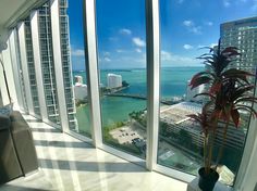 a room with large windows looking out at the water and buildings in the distance,