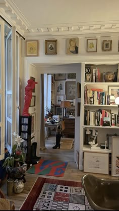 a living room filled with lots of furniture and bookshelves next to a window