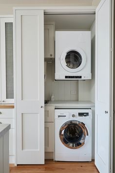 a washer and dryer in a small room with white cabinets on the wall