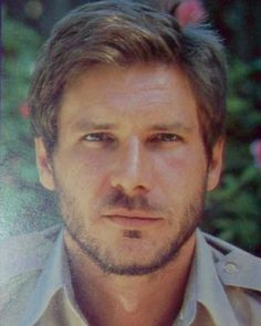 a close up of a person wearing a shirt and tie with flowers in the background