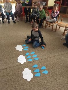 a group of children sitting on the floor playing with blue and white paper cut outs