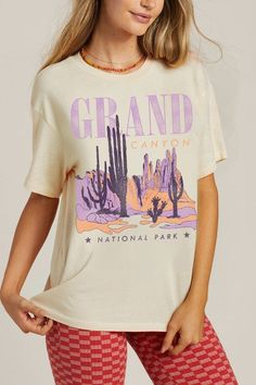 Our Grand Canyon Graphic Tee features a mineral wash, premium soft comfort cream fabric, short sleeves, distressed graphics, lavender and orange cactuses and desert canyons, with Grand Canyon National Park wording, and a straight hem. Fit: Relaxed. Pre shrunk. 100% Cotton. Machine Wash Cold. Tumble Dry Low. Model is wearing a size Small. Length 27", Bust 42". Lavender And Orange, Rock Tshirt, Cream Fabric, Grand Canyon National Park, Colourful Outfits, Camping Shirt, Shirt Outfit, Grand Canyon, National Park