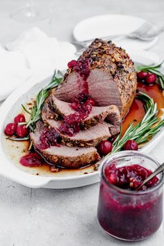 roast beef with cranberry sauce and rosemary garnish on a white plate