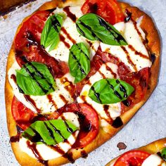 two pizzas with tomatoes, basil and mozzarella on them sitting next to each other