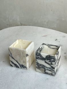 two marble candle holders sitting on top of a white table with a black and white design