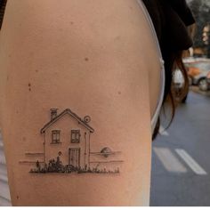 a woman's arm with a small house tattoo on the left side of her body