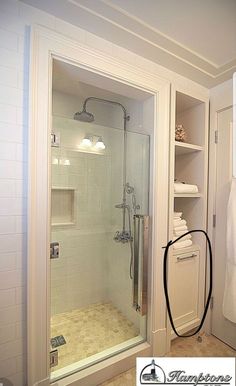 an instagramted photo of a bathroom with the shower stall door open and shelves full of towels