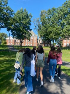 several girls walking down a path in front of a building