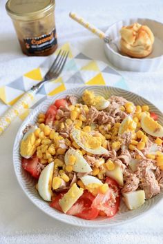 a white plate topped with meat and veggies next to a jar of jelly