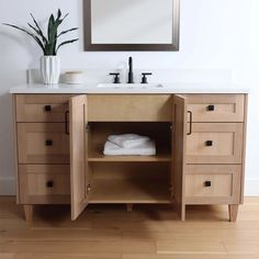 a bathroom vanity with wooden drawers and white towels