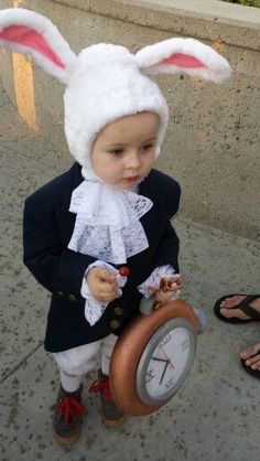 a small child dressed in bunny ears and holding a clock