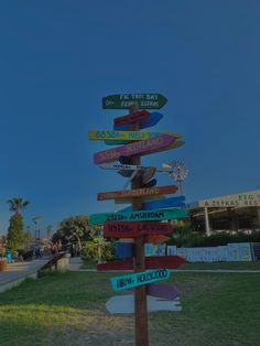 a wooden sign post with many different colored signs on it's sides in front of a building