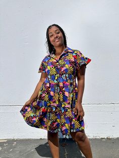 The Eloise is a sweet above-the-knee length dress. Made in our lightweight cotton poplin, this dress features a loose A-line silhouette with a collar, buttons all the way down the front, and has ruffled short sleeves and a tiered skirt that give it a fun whimsical vibe. 👩‍🎨 Featuring artwork by Neya Knee-length Ruffled Shirt Dress For Day Out, Casual Shirt Dress With Ruffles For Dress Down, Casual Shirt Dress With Ruffles For Dress Down Occasions, Summer Ruffled Collared Dress, Summer Collared Ruffle Dresses, Summer Collared Dress With Ruffles, Cotton Mini Shirt Dress With Ruffles, Cotton Shirt Dress With Ruffles For A Day Out, Casual Collared Shirt Dress With Ruffles