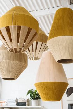 three wooden lamps hanging from the ceiling in a room with white walls and metal beams