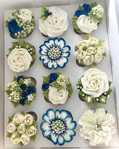 cupcakes decorated with white and blue flowers in a box