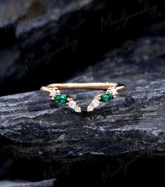 a gold ring with green and white stones sitting on top of a black stone slab