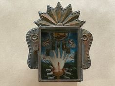 an ornate metal frame with a hand painted on the front and sides, hanging from a wall