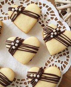 heart shaped cookies decorated with chocolate and pearls on a doily next to utensils